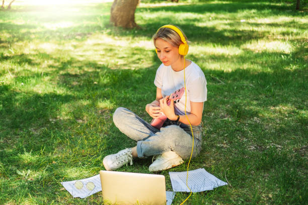 jolie adolescente jouant du ukulélé devant la caméra. cours de musique en ligne. - musical instrument nature outdoors musician photos et images de collection