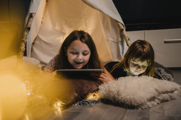 istock Two little girls using digital tablet in teepee tent 1326205039