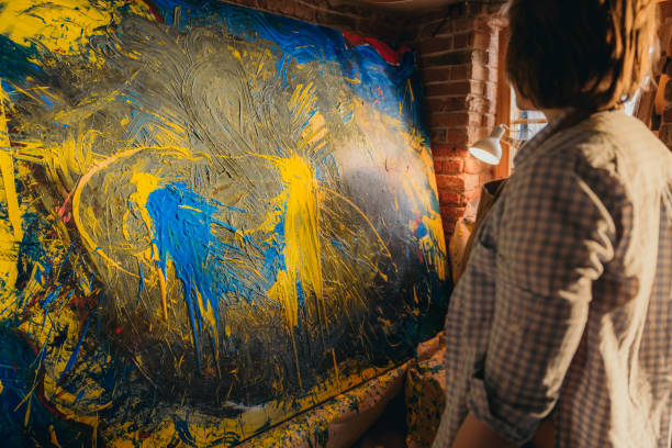 istock Female artist looking at her painted artwork on canvas 1326208226
