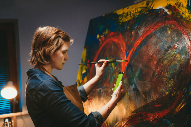 istock Artist referencing artwork on smartphone while painting on canvas 1326208367