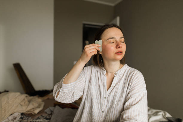 портрет молодой женщины, делая гуашь массаж лица в домашних условиях - spooning стоковые фото и изображения
