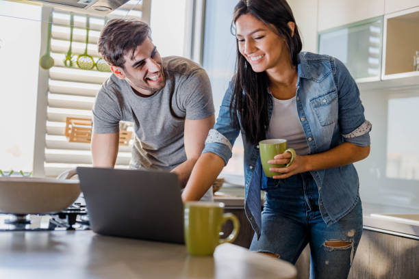 istock Young happy couple using laptop in the kitchen. 1326211040