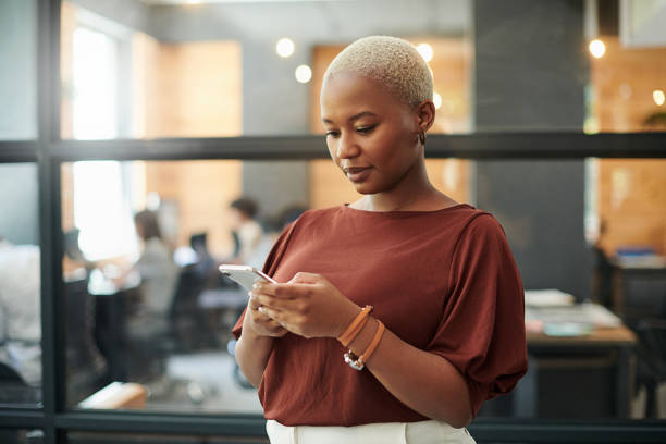 ujęcie młodej bizneswoman za pomocą smartfona w nowoczesnym biurze - businesswoman business women african descent zdjęcia i obrazy z banku zdjęć