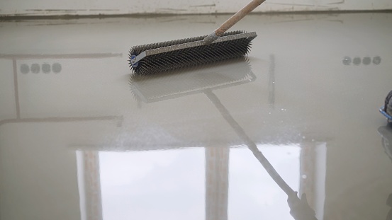 Leveling the floors with a cement mixture. Needle roller for self-leveling floor. Epoxy concept. concrete floor. on the horizon. close-up. needle roller to remove air bubbles. there is toning. then there will be painting. Needle roller for self-leveling