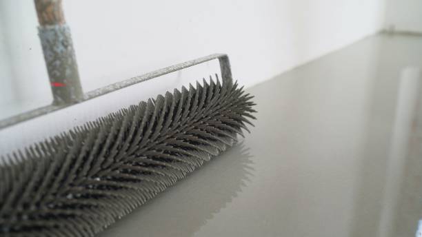 istock Leveling the floors with a cement mixture. Needle roller for self-leveling floor. Epoxy concept. concrete floor. on the horizon. close-up. needle roller to remove air bubbles. there is toning. then there will be painting. Needle roller for self-leveling 1326214345