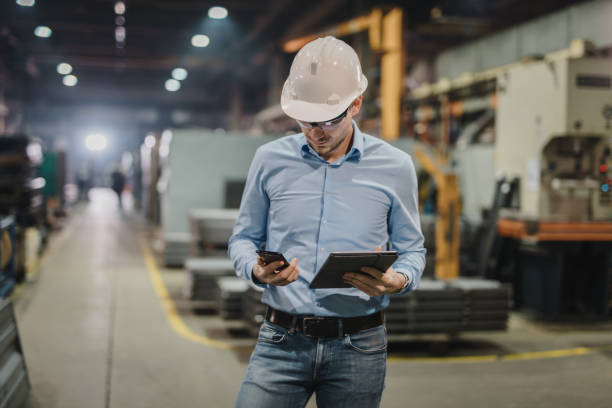 istock Male engineer using touch pad and mobile phone in factory 1326217560
