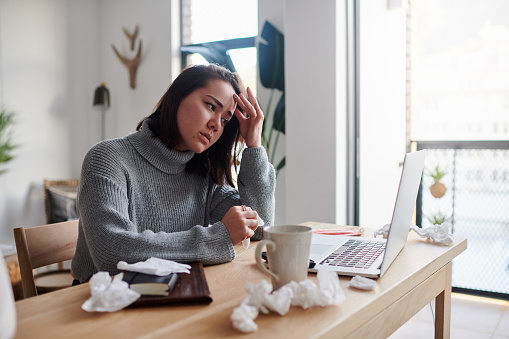 Shot of a woman feeling unwell while working from home