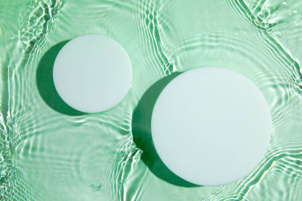 istock Two empty white circle podium on transparent green water background 1326222146