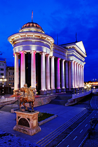 Night view of the Archaelogical Museum of Macedonia in the city center of Skopje. In the foreground is seen an equestrian statue of Karposh a national hero. \nThis museum has a collection of over 7000  objects of extraordinary historical, cultural, and art values. These artifacts tell stories of the local inhabitants, their material and spiritual cultures from early prehistory until the end of the Ottoman period early in the 20th century.