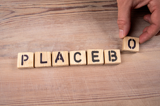 PLACEBO. Wooden alphabet letters and a man's hand on a wooden background.