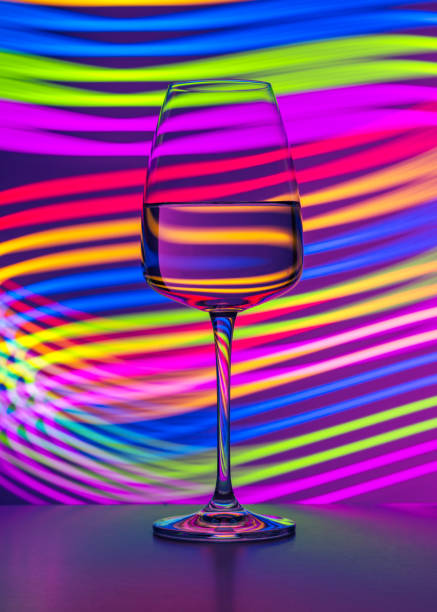 élégant verre de cristal rempli de vin rouge sur un fond bleu peint de lumière colorée. reflets et réfractions de lumière, stries lumineuses, ambiance club, style de vie, abstrait. - wineglass glass crystal studio shot photos et images de collection