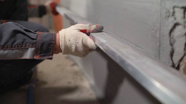 istock Plasterer at work on construction site, leveling walls and checking quality. Industrial worker on construction site. Worker leveling walls from mortar 1326226330