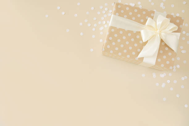 istock beige gift wrapped in dotted paper with white bow on beige background 1326226334