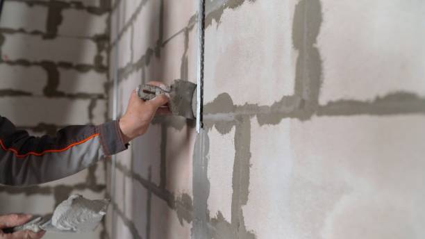 istock A professional bricklayer-builder by a manual craftsman applies cement mortar to the primed wall. A worker applies plaster to the wall with a trowel 1326226572