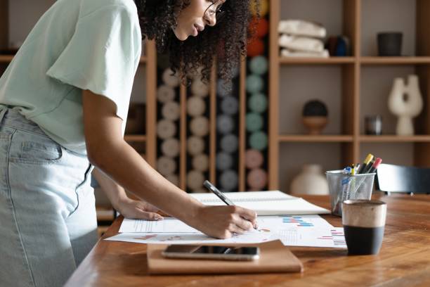 istock Mixed-race beautiful businesswoman working with papers while standing in modern office 1326227108