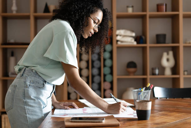 istock Mixed-race beautiful businesswoman working with papers while standing in modern office 1326227114