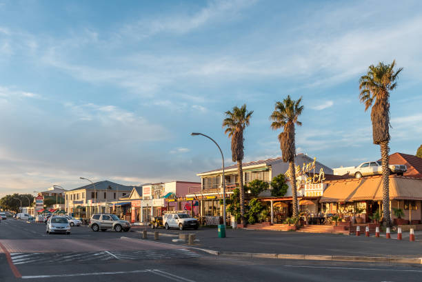 Panoramic sunset street scene in Gordons Bay Gordons Bay, South Africa - April 12, 2021: Panoramic sunset street scene in Gordons Bay in the Western Cape Province. People and vehicles are visible gordons bay stock pictures, royalty-free photos & images