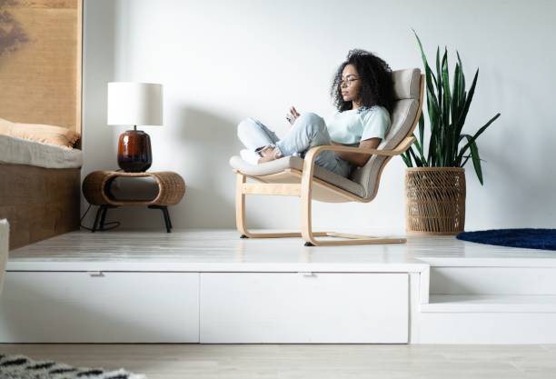 istock Beautiful Young Mixed race Woman Using Smartphone, while Sitting on the Chair, Surfs Internet, Posts on Social Media 1326228657