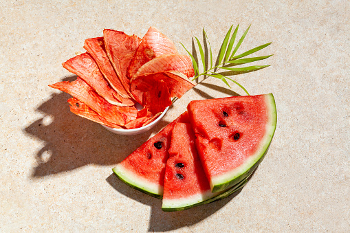 Winter supplies: slices of dried watermelon with fresh pieces on light background with deep shadow.