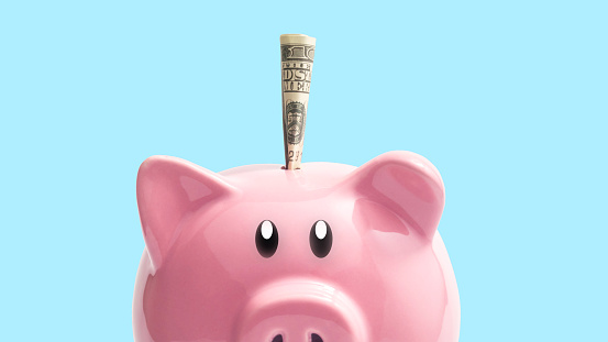 dinero en una alcancía rosa sobre fondo azul. concepto de ahorro de dinero. photo