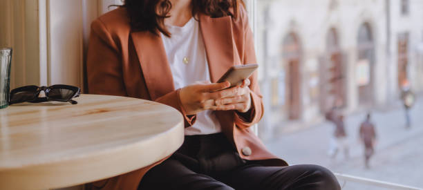 mujer sentada en el café enviando mensajes de texto por teléfono - unrecognizable person laptop holding women fotografías e imágenes de stock