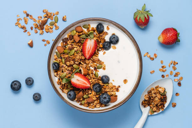 Healthy breakfast with homemade granola Healthy breakfast with homemade granola, berries and greek yogurt. Oatmeal, nuts, strawberries and blueberries in bowl on bright blue background. Copy space, top view granola photos stock pictures, royalty-free photos & images