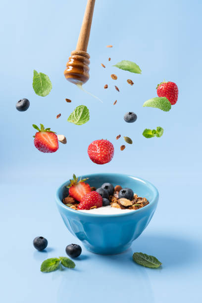Granola with yogurt and berries in bowl Granola with yogurt and berries in bowl. Food levitation. Healthy breakfast. Blue background, side view granola photos stock pictures, royalty-free photos & images