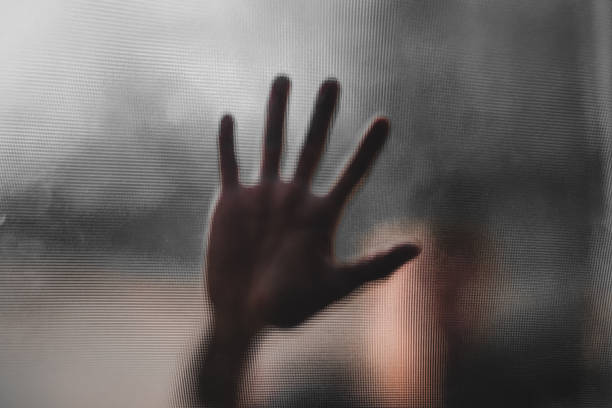 istock Shadow of blurry hand behind frosted glass 1326236854