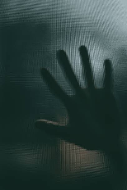 istock Shadow of blurry hand behind frosted glass 1326236995