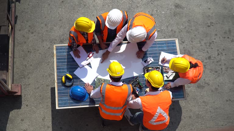 Group of Solar power plant Engineers Team Meeting and discussion to brainstorming with blueprint on solar cell top table Planning for a New Project of Environmental Power at construction site outdoors