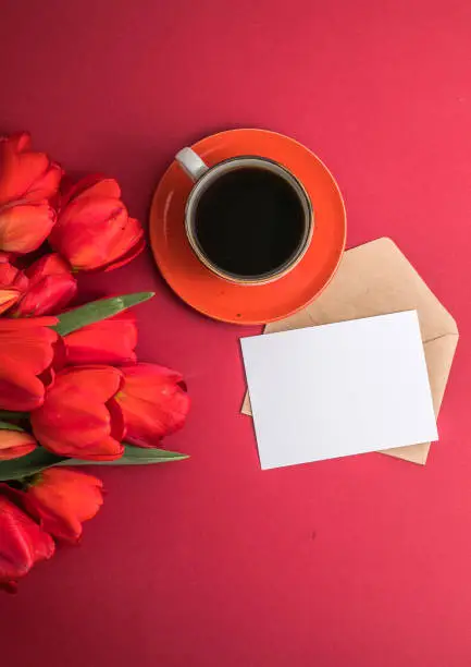 Photo of Bouquet of red  tulips and coffee cup arrangement with a lot of copy space for text. Spring mood concept. Greeting card for Birthday, Woman, Mother's Day, Wedding, Valentines day.