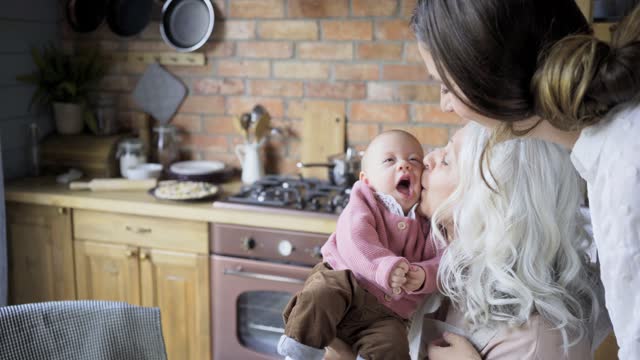 aged lady plays with granddaughter sitting in daughter hugs