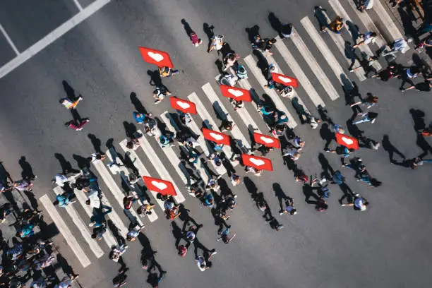 Photo of Crowd of people at pedestrian crossing with social heart icons and likes - overhead shot