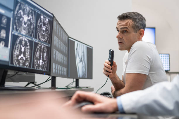 istock Male radiologist speaking into a dictation recorder while looking at MRI scan 1326240222