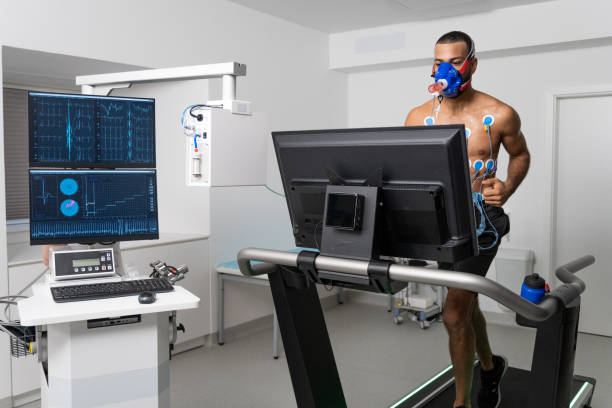 Mid adult man running on the treadmill ergometer during a cardiopulmonary stress test Male athlete running on the treadmill taking a cardiopulmonary stress test in clinic. stress test stock pictures, royalty-free photos & images