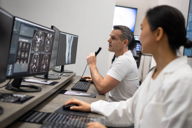 istock Male radiologist speaking into a dictation recorder while looking at MRI scan 1326240306