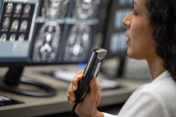 female radiologist speaking into a dictation recorder while looking at mri scan - 聽寫 個照片及圖片檔