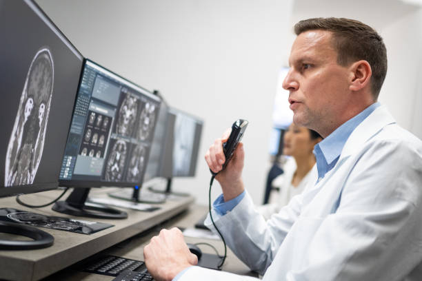 istock Male radiologist speaking into a dictation recorder while looking at MRI scan 1326240420