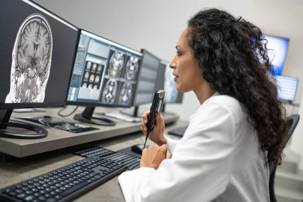 istock Female radiologist speaking into a dictation recorder while looking at MRI scan 1326241033