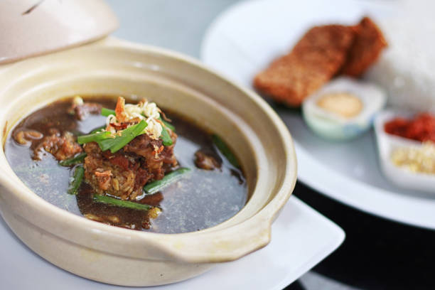 Rawon is traditional Javanese black meat soup with strong rich tasting traditional Indonesian spices, served with sprouts, and salted egg. Side View. Selective Focus