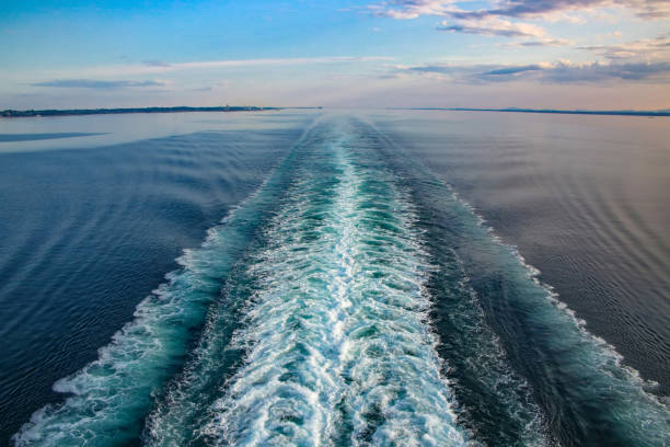 Wake of a ship across Ocean while sailing the Baltic beautiful day. Wake of a ship across Ocean while sailing into the Norwegian fjords, on a beautiful day. Purple and blue light reflecting on the sea and waves. Cruising the Baltic, North Sea and fjords, Northern Europe. spume stock pictures, royalty-free photos & images