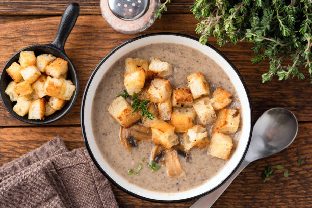 Mushroom cream soup with croutons in a bowl Mushroom cream soup with croutons in a bowl on wooden table background, top view cream soup stock pictures, royalty-free photos & images