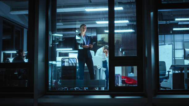 istock Shot from Outside: Businesswoman Working on a Tablet Computer in the Office. Manager Checking Emails while Standing by the Window. Employee Planning Financial Tasks and Business Development. 1326248348