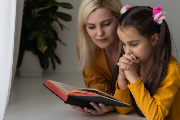 Religious Christian girl and her mother praying at home Religious Christian girl and her mother praying at home. cute girl praying stock pictures, royalty-free photos & images
