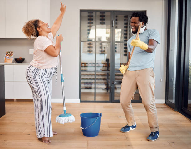 shot of a young couple singing and dancing while cleaning at home - spring cleaning women cleaning dancing imagens e fotografias de stock