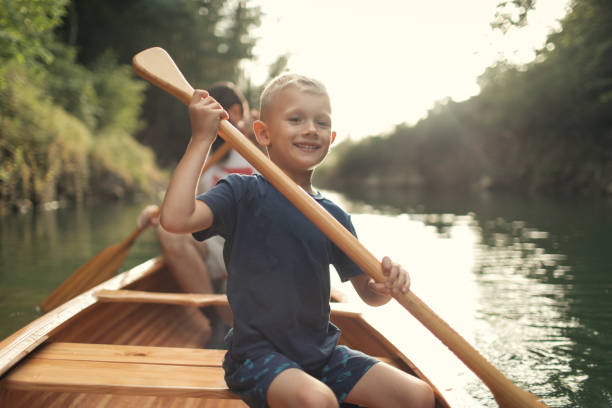 cute young boy canoeing on the lake with his dad - family kayaking kayak canoeing imagens e fotografias de stock