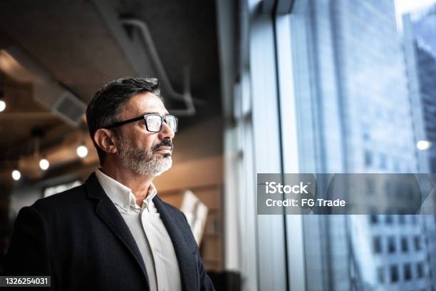 Mature Businessman Looking Out Of Window Stock Photo - Download Image Now - Businessman, Business, Contemplation
