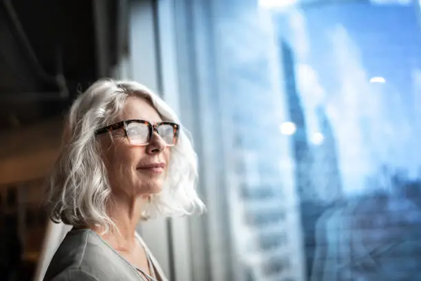 Photo of Mature businesswoman looking out of window.