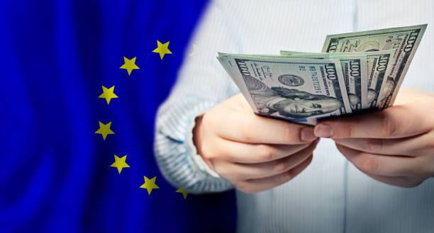 hände mit dollarscheinen auf der flagge der europäischen union hintergrund, konzept des globalen handels an der börse, fallenund und steigende preise für weltwährung - currency exchange currency european union currency dollar stock-fotos und bilder