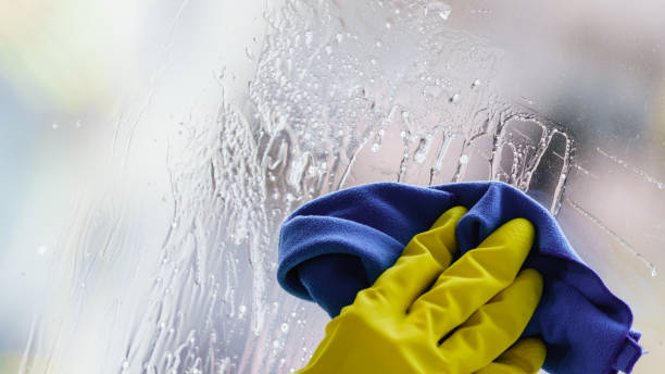 istock Gloved hand cleaning window rag and spray 1326256099